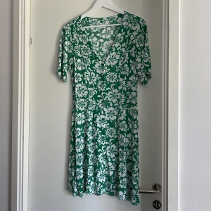 Grön Klänning - Säljer denna gröna klänningen med vita blommor på! Den kommer ifrån MONKI och är i storlek XS! Använd en gång så den är i väldigt bra skick! 💝