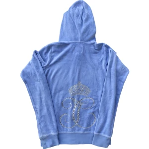 Blå Juicy Couture Huvtröja - Blå velour huvtröja från Juicy Couture. Snyggt tryck med rhinestones på baksidan. Storlek XL (12-14) eller XS. Bra skick förutom en liten prick, ställ gärna frågor!😊