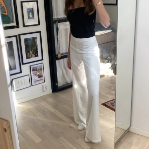 Långa Vita kostymbyxor - Vita supersköna byxor i ett siden-liknande material! I modell tall så dom går ner över fötterna på mig som är 175cm.