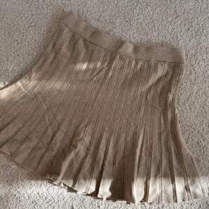 Biege kjol, är tajtare upptill och är utsvängd nertill. Super mjukt material, är mer en M än en L men super stretchig