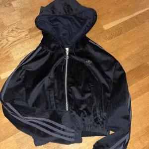 En svart cropped adidas zip hoodie. Den är i storlek 34 och brukar själv bära runt storlek S. Kort hoodie som sagt och inte använd så mycket och på länge. 