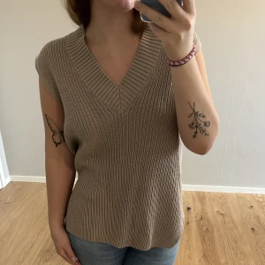 Stickad väst - Beige stickad väst. Inköpt i vintras men aldrig använd. Snyggare med en vit tröja under.