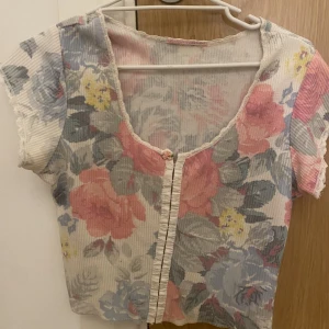Söt topp - Säljer denna knappt använda t-shirt / topp med knäppe där framme och ett blommigt mönster. Super fin men kommer inte till användning💗💗