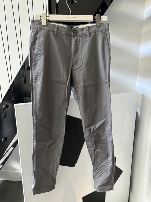 Club Monaco Chinos - Chinos från Club Monaco i grå färg. Storlek 30/32 Oanvända, endast legat i byrålåda.