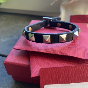 Valentino armband - Säljer detta super fina valentinoarbandet med nitar. Armbandet är använt och har haft defekter på bandet men är lagat och i gott skick nu. Äkthetsbevis och extra nitar till armbandet kommer med köpet. 