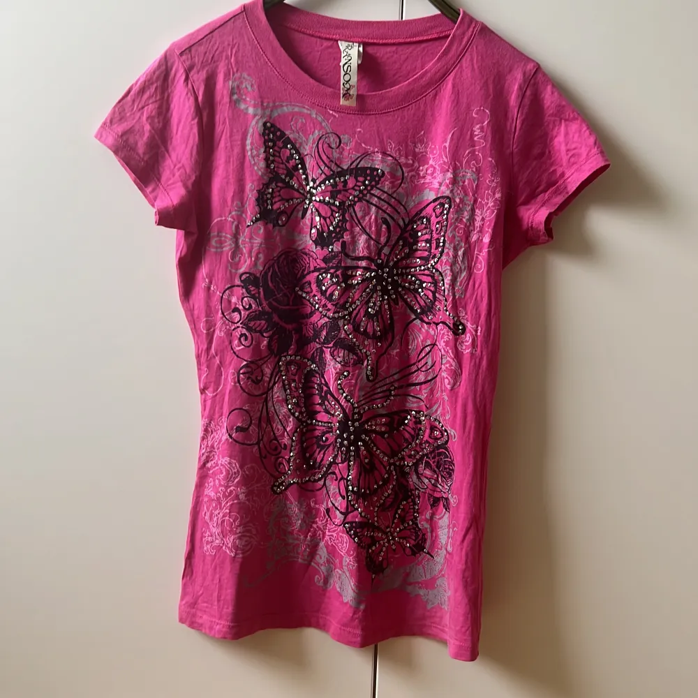 Rosa t-shirt med med fjärilar och andra detaljer. Fjärilarna är detaljerade med silvriga paljetter. Väldigt mycket 2000-tals känsla över den 💕🦋. T-shirts.