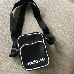 Väska  - En liten väska från adidas med två fack och ett mindre inuti. Helt oanvänd. Justerbara band🖤