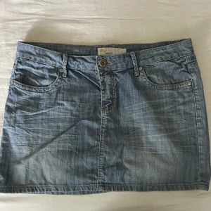 Lågmidjad jeanskjol - Supersöt ljusblå lågmidjad jeanskjol. Begagnat skick, finns en liten fläck på vänster bakficka, men syns knappt. Midjemått mätt rakt över: 43cm, längd: 37cm. Storlek XL, men passar även M och L beroende på önskad midjehöjd🫶💕