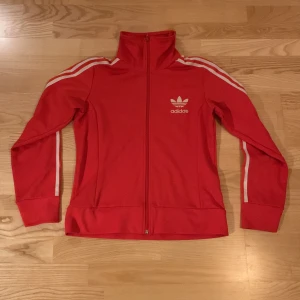 Adidas kofta - Röd/orange adidas kofta, bra skick nästan aldrig använd. Storlek s