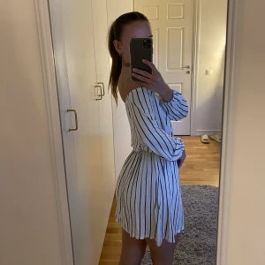 Klänning - En vit- och svartrandiga off shoulder klänning, gjord av ett mjukt och luftigt material