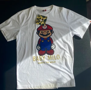 Bape T-Shirt - Nästan som ny vintage paljett Baby Milo tisha i storlek XL  Vet dock inte om den är äkta eller inte.  Skriv innan ni köper tack.   Mått: längd 74 cm, midja 52cm.