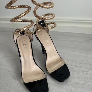 Klackar - Oanvända klackar från boohoo med ”metallorm” som slingras runt benet. I strl 39.