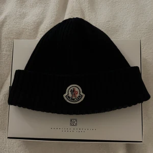 Moncler mössa - En moncler mössa i fint skick. 9/10 näst intill nyskick och sparsamt använd. Tags finns och nk boxen finns. Hör av dig vid några frågor. Priset är väldigt fast. Tar emot byten men obs Äktighetsbevis är ett krav!!