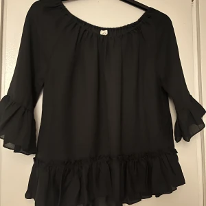 Blus  - En svart blus med fina volang detaljer, är i strl 158/164 men skulle säga att de motsvarar är xs/s