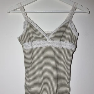 Sött, romantiskt linne - Pistage/vitrandig topp med spetsdetsljer och smala axelband. Tight passform. Inga skavanker.