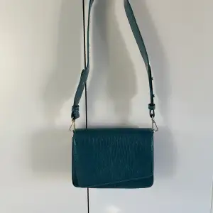 Liten handväska i orm imitation i en blå/grön färg, aldrig använd 