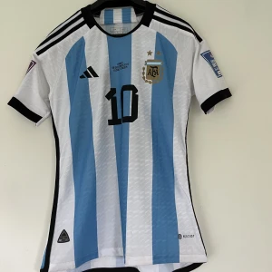 Fotbollströja Argentina Messi 10 - Argentinas tröja som de hade när de vann VM 2022 i mycket bra skick. Det är player version vilket innebär bättre material och bättre kvalitet. Storlek M