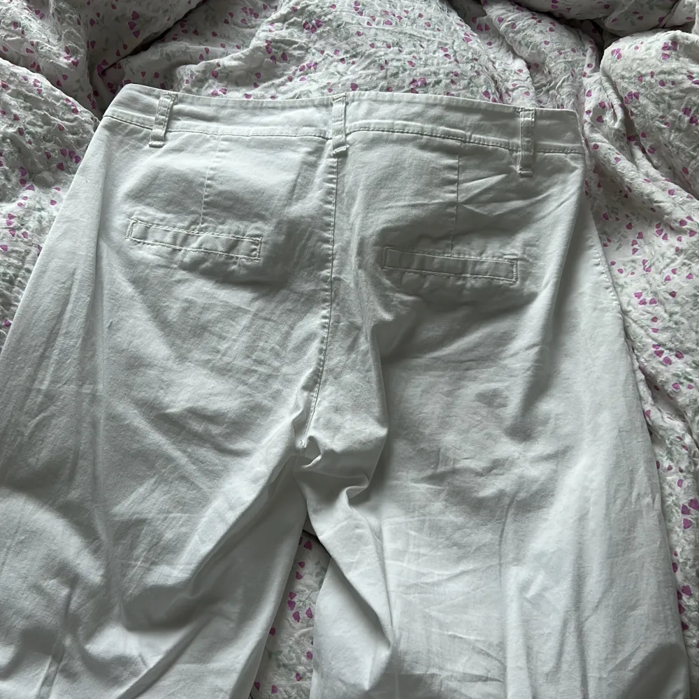 Ett par vita lågmidjade chinos/linnebyxor från DesignBySI. Sitter sjukt fint på och har utsvängda ben . Farkut & Housut.