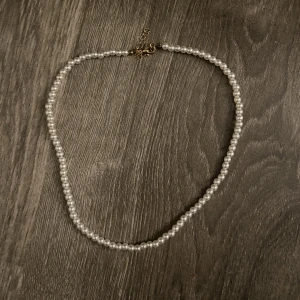 Pärlhalsband  - Pärlhalsband nytt. Tror det är gjort av plast, alltså ej äkta pärlor. Ca 49.5cm lång som störst och ca 44cm som minst. Detta är 1/3 pärlhalsbanden jag har lagt upp. 