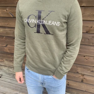 Calvin Klein tröja  - Säljer en grön ”Calvin Klein Jeans” tröja i använd skick utan några defekter! Storlek S