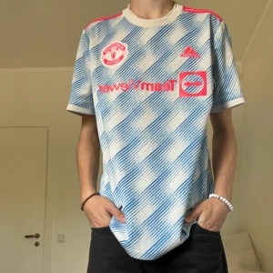 Manchester United borta 21/22 - Säljer denna feta Manchester United bortatröja från säsongen 21/22 med Rashford #10 på ryggen. Köpt direkt från Uniteds hemsida och är i 10/10 skick. Storlek L och passar mig bra som är 189cm.