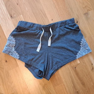 Söta pyjamasshorts  - Söta pyjamasshorts i grå färg med vita snören och vit spets vid sidorna. Höga i midjan och skönt material