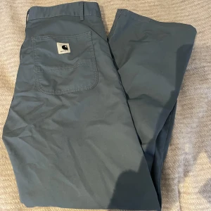 Blå Carhartt byxor  - Blå Carhartt byxor. I st:30.  På mig sitter de lite oversized, jag är 165 cm lång och har i vanliga fall 38/M på byxor. Använda fåtalet gånger! 