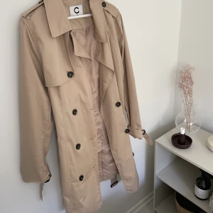 Trenchcoat  - Använd 1 gång  Storleken är XL men mer som en M. Jag som är en S köpte den för att den skulle vara lite lite oversized  Längd på mig som är 173 cm är ner till knäna