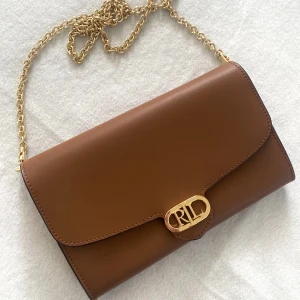 Ralph Lauren väska  - Använd fåtal gånger. Inga fläckar eller skador. Ligger förpackad i orginal tygpåse. Är beställd från Zalando.  Nypris 2200kr.  Säljer för 800kr.  Mått, 20x12 cm. 