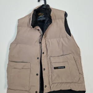 Canada Goose Väst Medium - Säljes Ganada Goose väst. Köpt för ca 20 år sen på NK. legat och dammat i garderoben fint skick lite skavanker vid fickorna se bilder.