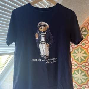En ralph lauren Poli bear t-shirt i marinblå Bra skick, inga hål, fläckar eller liknande. Helt intakt tryck av björnen på framsidan. Nypris: 1299kr Mitt pris: 350 ( diskuterbart vid snabb affär!)