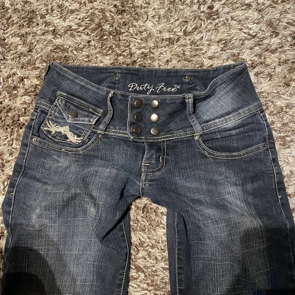 Utsvängda lågmidjade jeans med coola detaljer och knappar på fickorna.  Midjemått tvärs över: 36cm Innerbenslängd: 72cm . Jeans & Byxor.