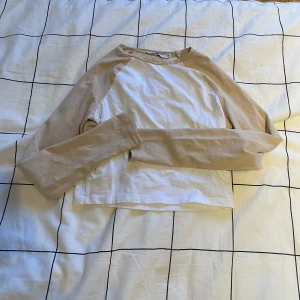 Tajt tröja - Säljer en tajt, beige-vit, cropped tröja från NA-KD i storlek XS.