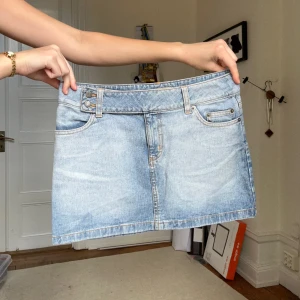 Jeanskjol - Jeanskjol i ljus tvätt. Lite stretchig i midjan. Knäppes i sidan med två knappar. Midja tvärs över 39, längd 33 cm.