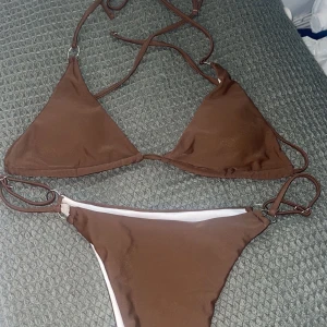 Bikini brun - Superfin brun bikini! Banden på trosorna går att anpassa efter sig själv och överdelen knyter du själv i nacken och i ryggen. Trosan är i en stringmodell och toppen är liten i storleken. Helt oanvända både delarna
