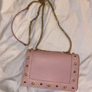 Axelremsväska  - Väldigt fin nästan oanvänd väska från Don Donna. Lång axelrem i guldkedja och litet fack inuti. Passar för dig som söker en liten fin väska som inte behöver för plats med så mycket! Fråga mig för mer bilder🩷💖