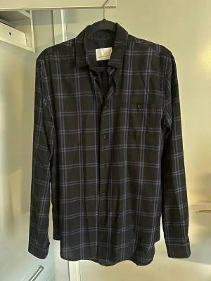 Overshirt från Samsøe - Hej! Säljer nu en Overshirt/Skjorta från Samsøe i nyskick. Den är svart med trendigt mörkblått flanell tryck!   Hör av dig vid frågor