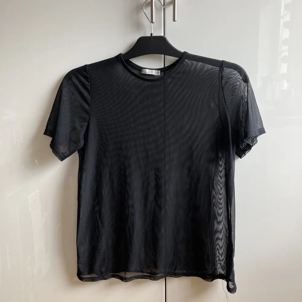 Svart mesh T-shirt i storlek XS från Nelly. Tunt och skönt material, ganska lång så går bra att stoppa in den om man vill det. Sparsamt använd.. T-paidat.