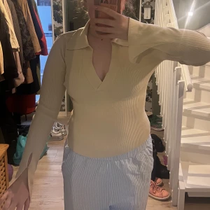Beige långärmad tröja - Är 178, tröjan sitter bra, skär sig tyvärr med min hudfärg! Lite åt det gulare hållet. V-ringad med krage. Tröjan har långa ärmar, detaljen syns på bilden! Ej använd. Tröjan är från Gina tricot