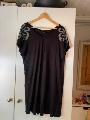 Klänning - Svart klänning med glitter på axlarna. Storlek: L. 