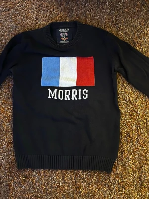 Mörkblå stickad tröja Morris - Mörkblå stickad tröja från Morris med fransk flagga 🇫🇷 ‼️Skicket är okej på tröjan dock syns det att den är gammal ‼️Tröjan har rund halsringning och ribbade muddar vid ärmslut och nederkant. Perfekt för dig som gillar klassisk och stilren design.