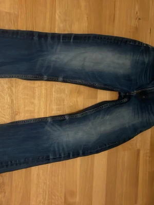 Mörkblå slim fit jeans med slitningar - Snygga mörkblå jeans med slitna detaljer och tvättade partier på låren och knäna. Modellen är slim fit med raka ben och klassisk femficksdesign. Perfekta för en avslappnad och trendig look. Materialet är troligtvis bomull med stretch.