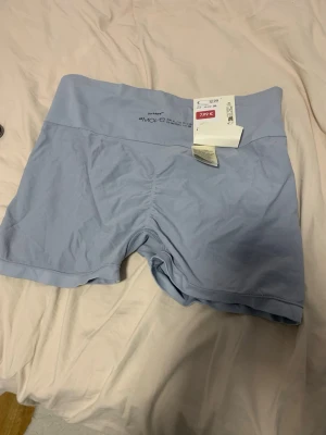 Ljusblå seamless shorts från H&M Move - Säljer ett par ljusblå seamless shorts från H&M Move. De har hög midja och är tillverkade i ett mjukt, stretchigt material som passar perfekt för träning. Shortsen har en diskret rynkning bak och bred linning för extra komfort.