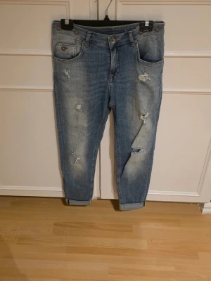 Blå slitna boyfriend jeans 157 - Säljer ett par ljusblå boyfriend jeans från 157 med slitningar och hål på benen.