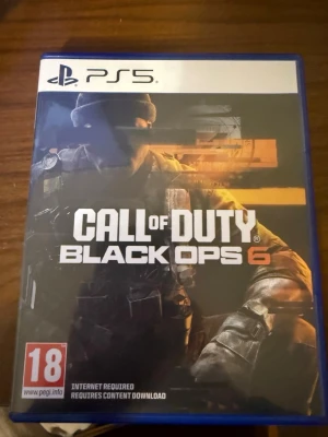 Call of Duty Black Ops 6 PS5 - Call of Duty Black Ops 6 till PlayStation 5. Omslaget är svart och orange med en soldat i fokus. Spelet är ett actionfyllt FPS med kampanj, multiplayer och zombies-läge. PEGI 18. Kräver internetanslutning och nedladdning av innehåll.