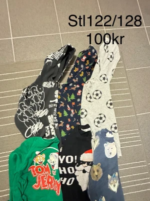 Färgglada hoodies med tryck stl 122/128 - Säljer ett gäng coola hoodies i storlek 122/128. Blandade motiv som Tom & Jerry, fotbollar, julmotiv, vargar och grafiska tryck. Flera olika färger som svart, grå, grön och blå. Perfekta för dig som gillar unika och roliga prints!
