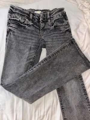 Grå tvättade raka jeans - Säljer ett par grå tvättade jeans med rak passform och klassisk femficksdesign. Jeansen har normal midja och bälteshällor. Materialet är denim i bomull och färgen är snyggt urtvättad grå som ger en cool vintagekänsla.