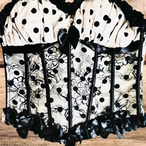 Korsett i äkta Mouline Rouge-stil! - Jättefin korsett i cremevit satin med svart spets, dragkedja i sidan, justerbara axelband, rygglapp, mjuka skenor fram och snörning bak som kan justeras flera dm. Mått: H: 40 cm (exkl. axelband) 80 cm runtom på innersta snörning med utrymme för extra 20 cm. Perfekt skick.