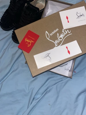 Svarta spikes sneakers Christian Louboutin - Säljer ett par svarta sneakers från Christian Louboutin med coola spikes över hela skon. Skorna har dock tappat en spik. Och har blivit lite sliten där inne. Skorna har en klassisk låg siluett och är tillverkade i mocka med matchande svarta snören. Perfekta för dig som vill sticka ut med exklusiv design. Men prisen kan diskuteras tveka inte om att skicka ett meddelandet.