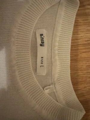Vit  stickad tröja från Sinsay - En stilren beige stickad tröja från Sinsay med rund halsringning och långa ärmar. Tröjan har ribbade muddar vid halsen och är tillverkad i ett mjukt material som passar perfekt till lager på lager. Enkel och clean design som funkar till det mesta.